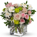 Clear glass cube arrangement of soft pink roses, mid pink spray roses, white alstroemeria & statice, green cushion spray chrysan