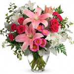 Clear glass vase arrangement of hot pink spray roses, mid pink asiatic lilies, white alstroemeria, hot pink asters, accented wiC
