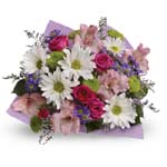 A lovely mix of fresh flowers in breezy shades of pink, white, lavender and more, all tied up with a big pink bow.