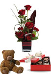 Roses, the traditional flower of love, receive a modern twist in this imaginative arrangement with box of chocolates and a teddy